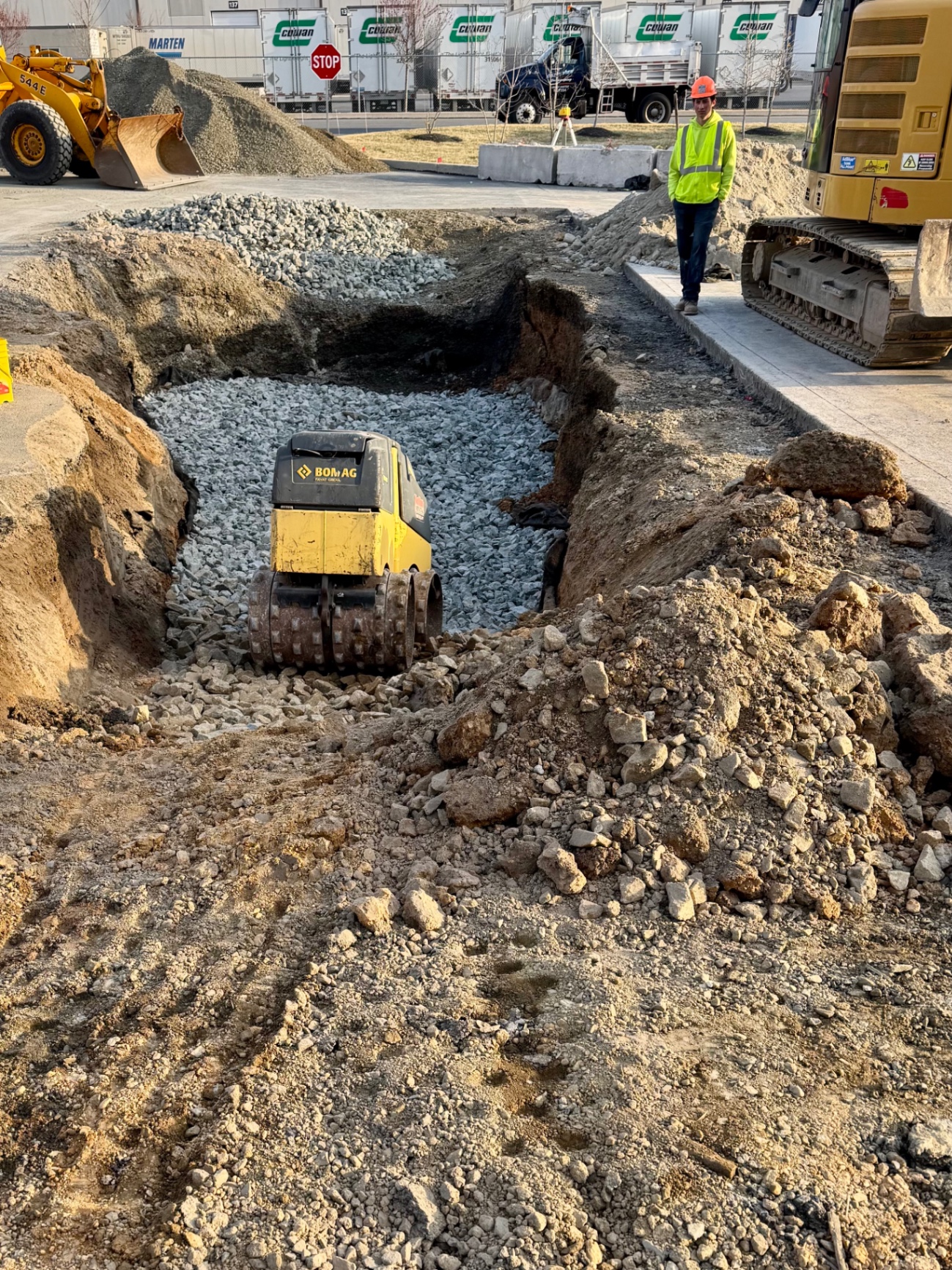 Compaction equipment working in a stone-filled excavation area