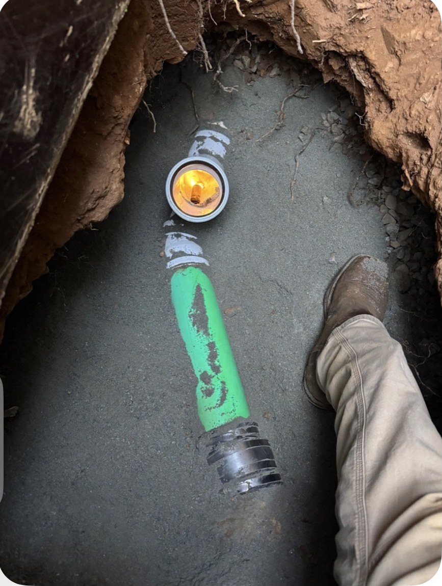 New green sewer lateral pipe with couplings installed in an open excavation