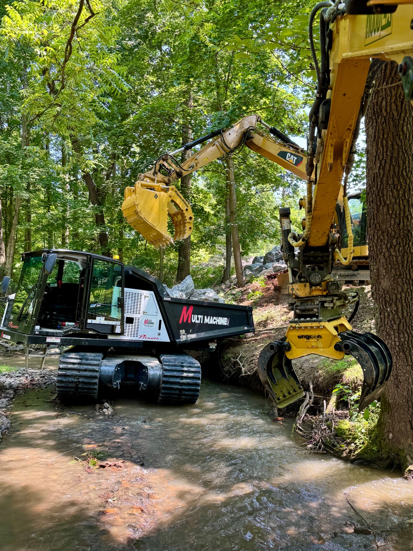 Heavy equipment restoring a stream bank in a wooded waterway