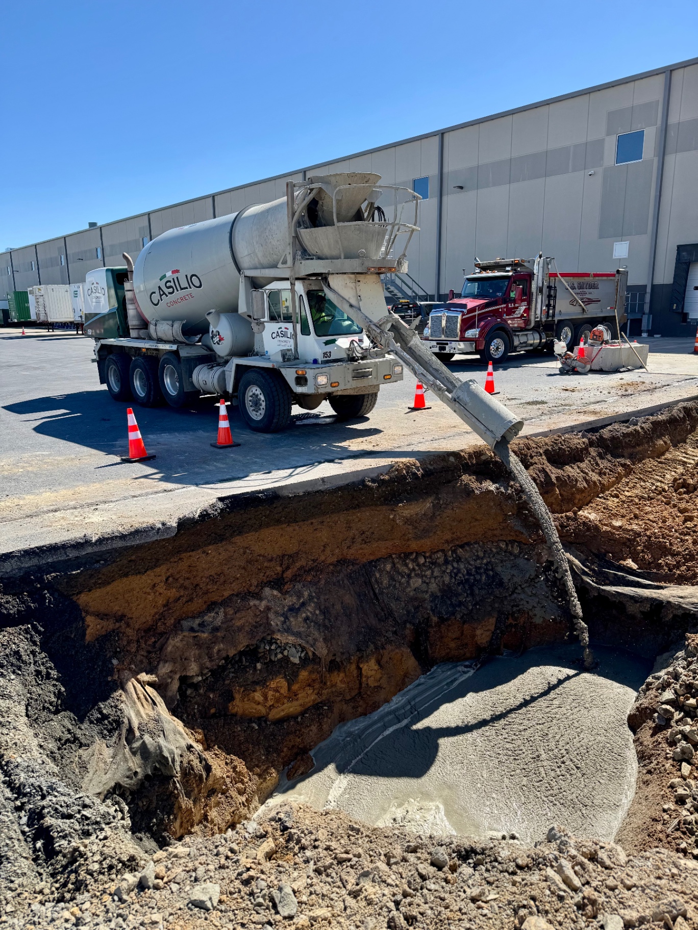 Concrete being poured into a utility trench on a commercial site