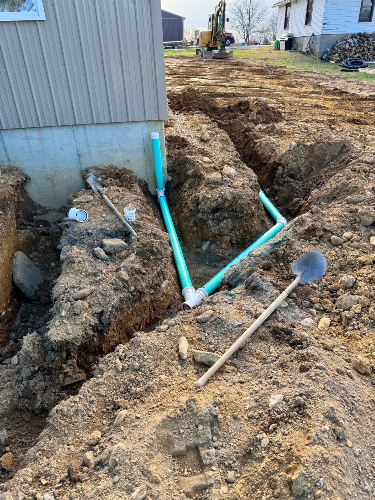 Drainage piping installed in an open trench alongside a commercial building